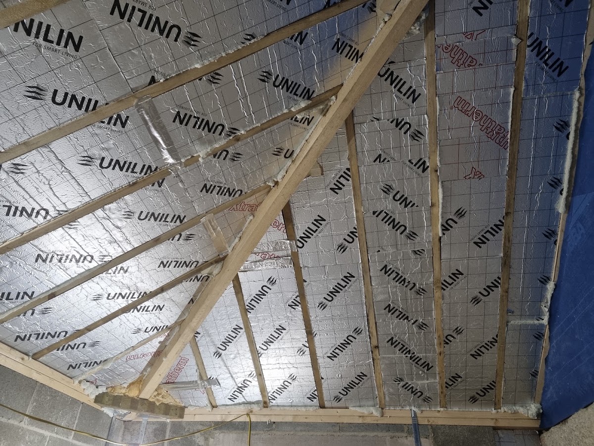 Insulated loft roof with rigid board fitted between the rafters
